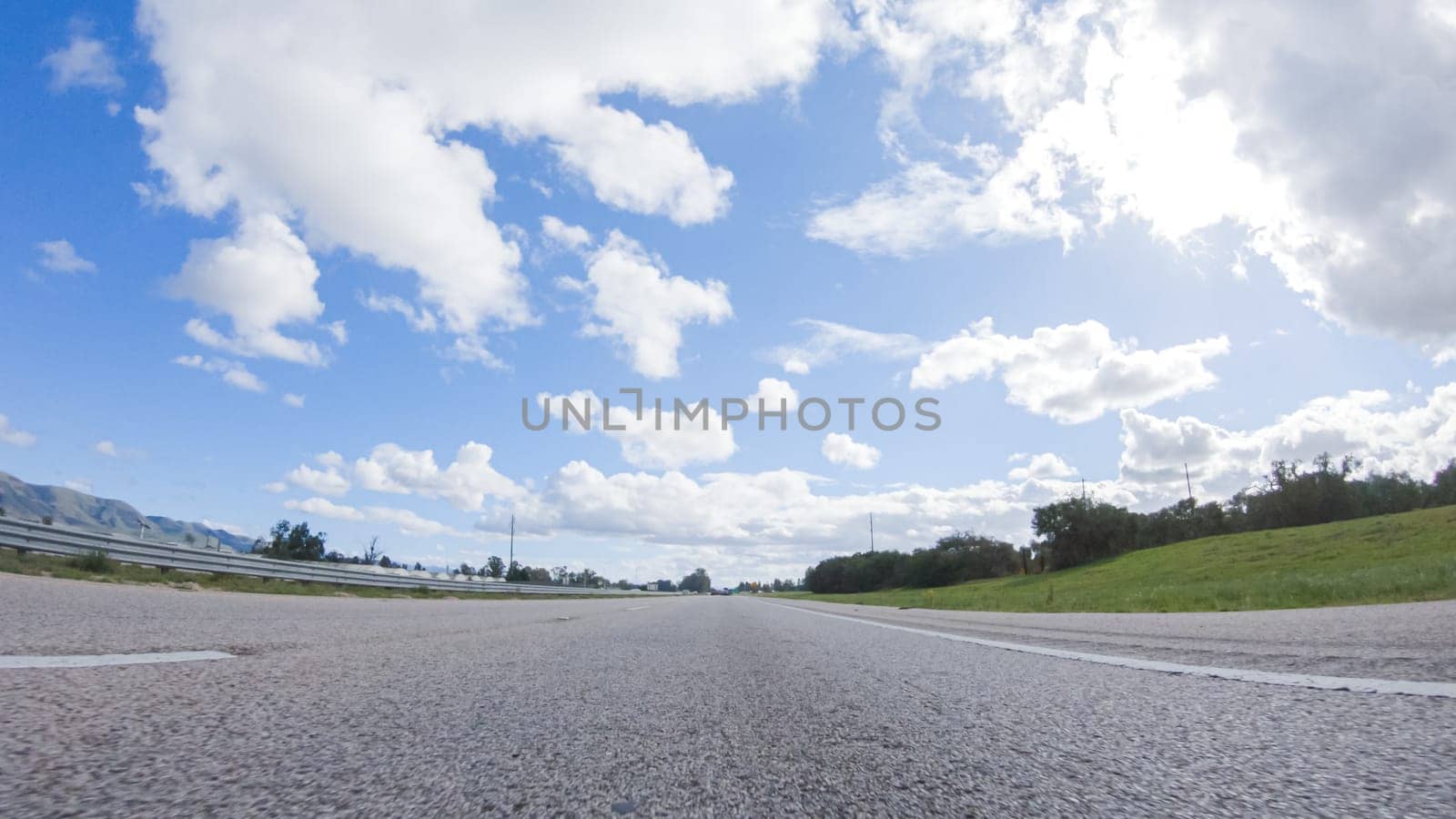 On a clear winter day, a car smoothly travels along Highway 101 near Santa Maria, California, under a brilliant blue sky, surrounded by a blend of greenery and golden hues.