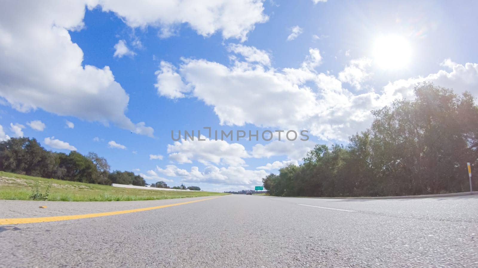 On a clear winter day, a car smoothly travels along Highway 101 near Santa Maria, California, under a brilliant blue sky, surrounded by a blend of greenery and golden hues.