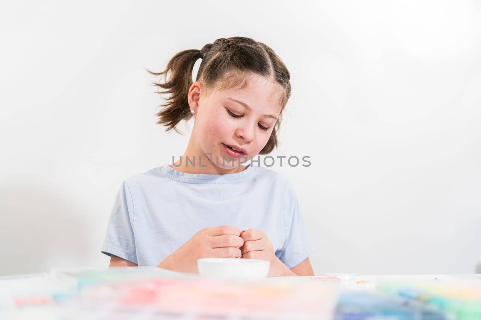 Little girl enjoys crafting colorful bracelets with vibrant clay beads set.