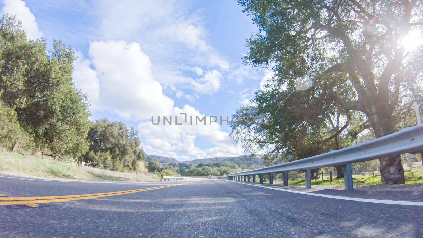 Vehicle is cruising along the Cuyama Highway under the bright sun. The surrounding landscape is illuminated by the radiant sunshine, creating a picturesque and inviting scene as the car travels through this captivating area.