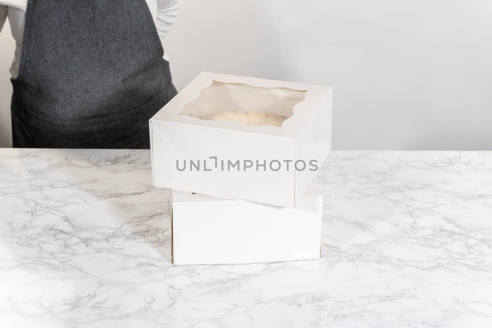 The freshly baked bundt cakes are carefully nestled into white paper boxes, preparing them for secure transportation while maintaining their delectable appearance.