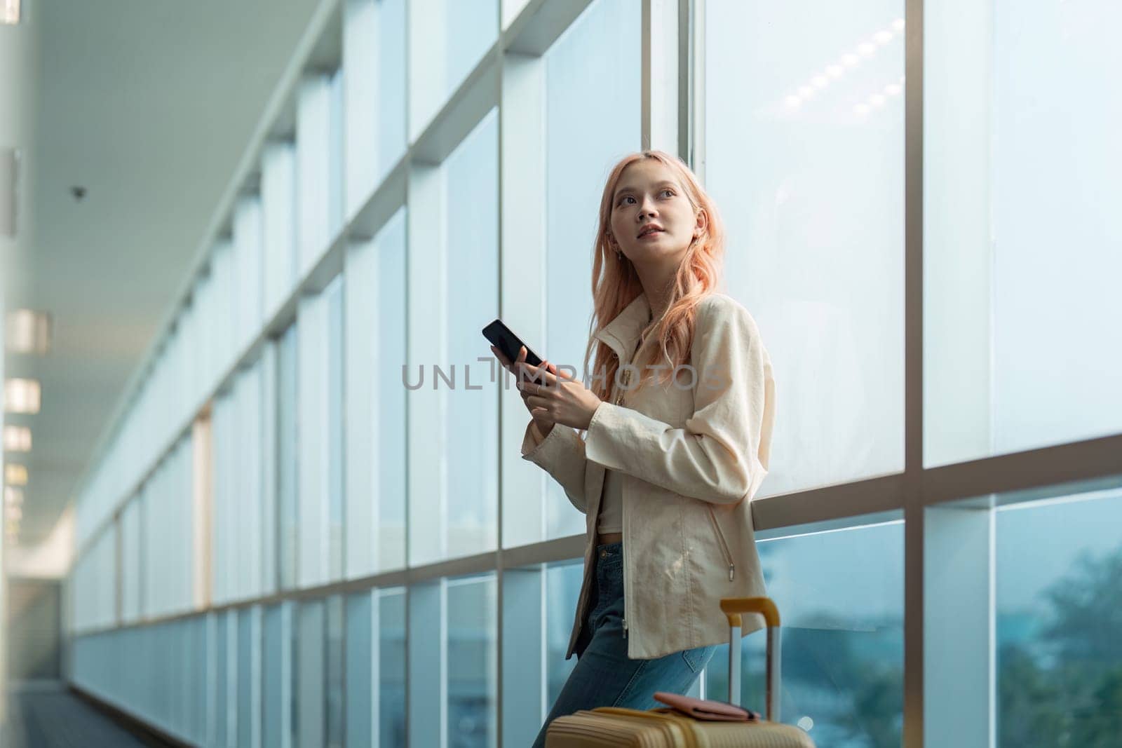 Traveler woman asian in airport and luggage for vacation, smile and holding the phone check boarding ticket. Female traveler with suitcase, international and departure with passport and trip.