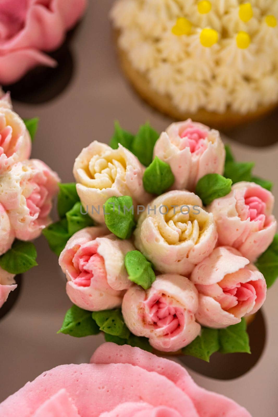 Encased in a pristine white paper cupcake box, each gourmet cupcake is a work of art, adorned with buttercream frosting flowers beautifully designed to resemble vibrant roses and tulips.