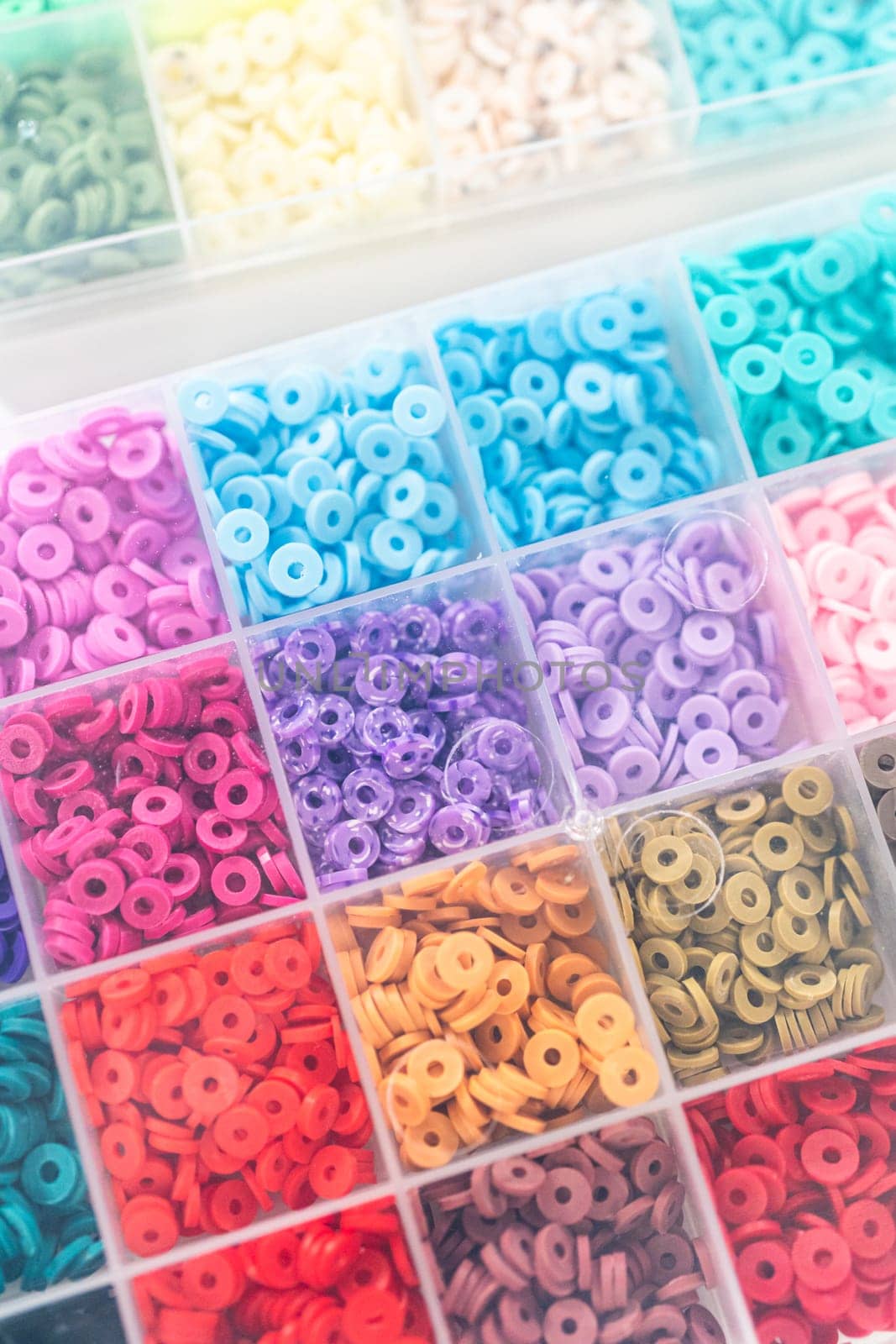 Assorted clay bead boxes neatly arranged on a white table, awaiting a creative kids' craft project.