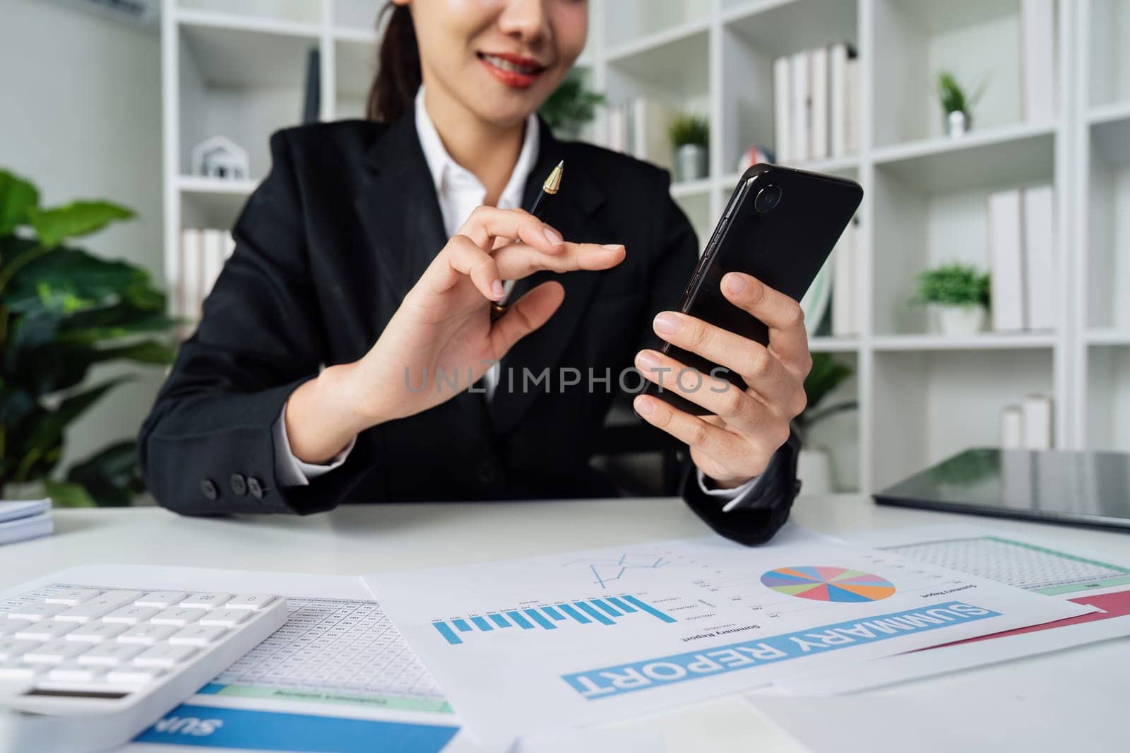 business woman using smartphone while working on laptop, synchronize data between computer and gadget in office, use corporate devices and business application.