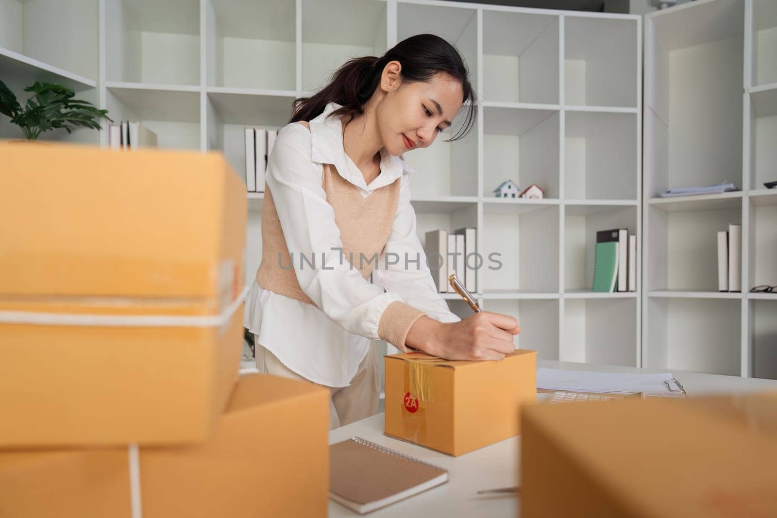 Young business woman entrepreneur online shipment business is preparing packages to send to customer. e-commerce concept by itchaznong