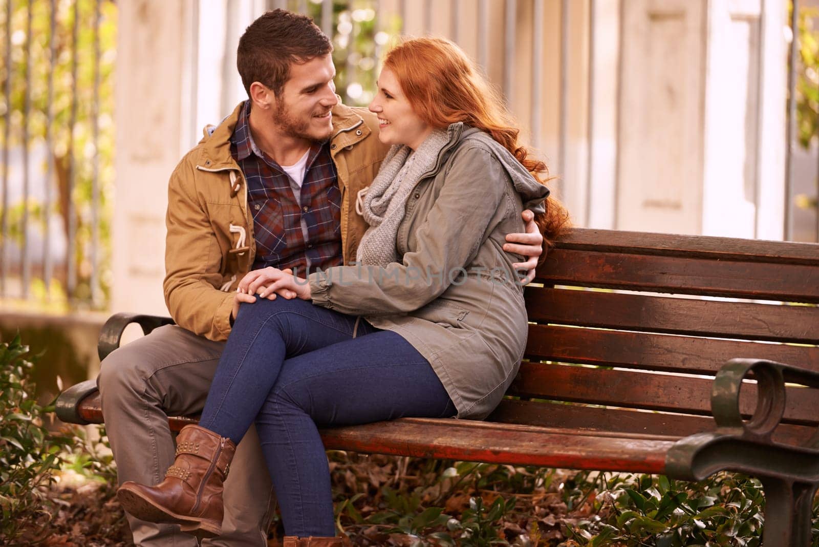 Couple, love and sitting with hug at park in cold weather or winter, together and smile in London. Relationship, commitment and bonding for romance with soulmate, care and happiness on holiday by YuriArcurs