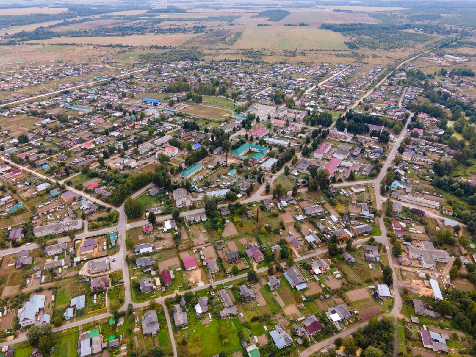 Aerial view of dwelling houses between roadways and meadows with trees in region of Kirov Russia