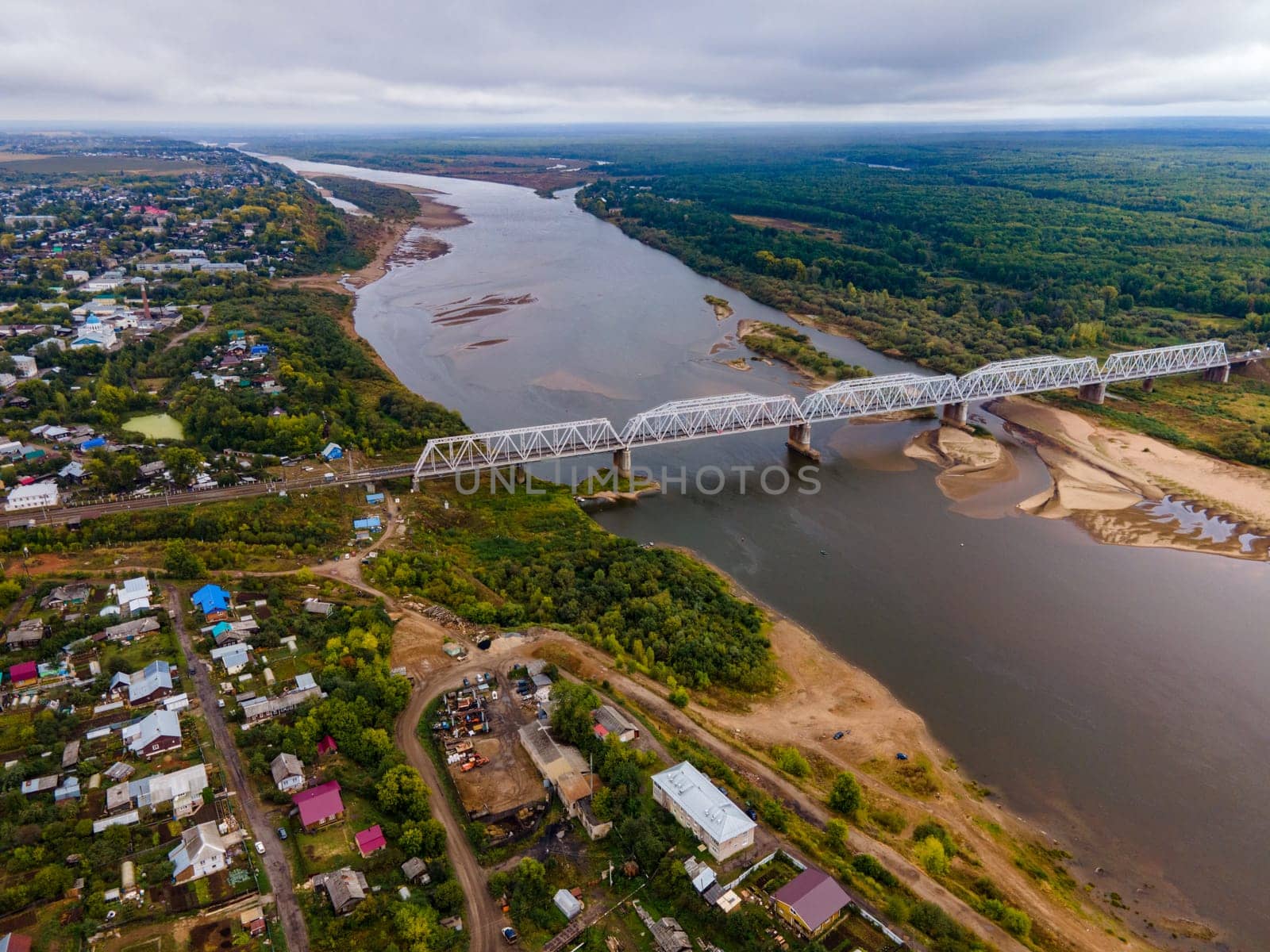 Drone view of bridge above river between lush trees and dwelling buildings in region of Kirov Russia