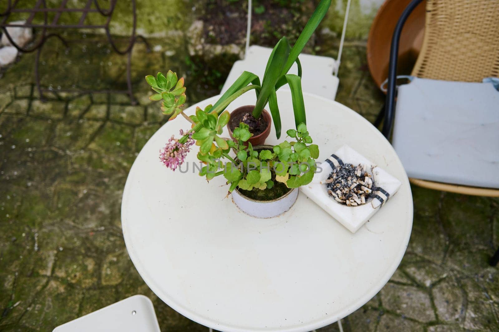 View from above of a white table with chair in the garden. Ashtray with cigarette butts on the table. The concept of lung diseases. Lung cancer awareness campaign