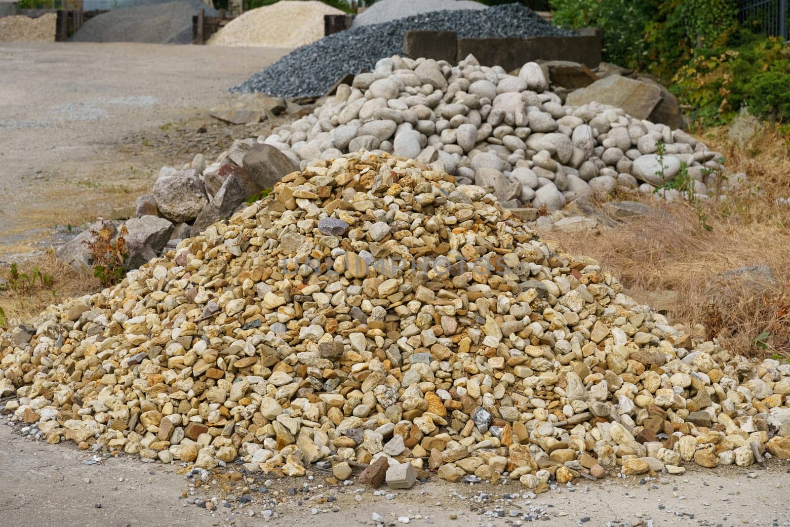 A cluster of rocks piled neatly at the edge of a road, likely placed for construction or landscaping purposes, under a clear blue sky.