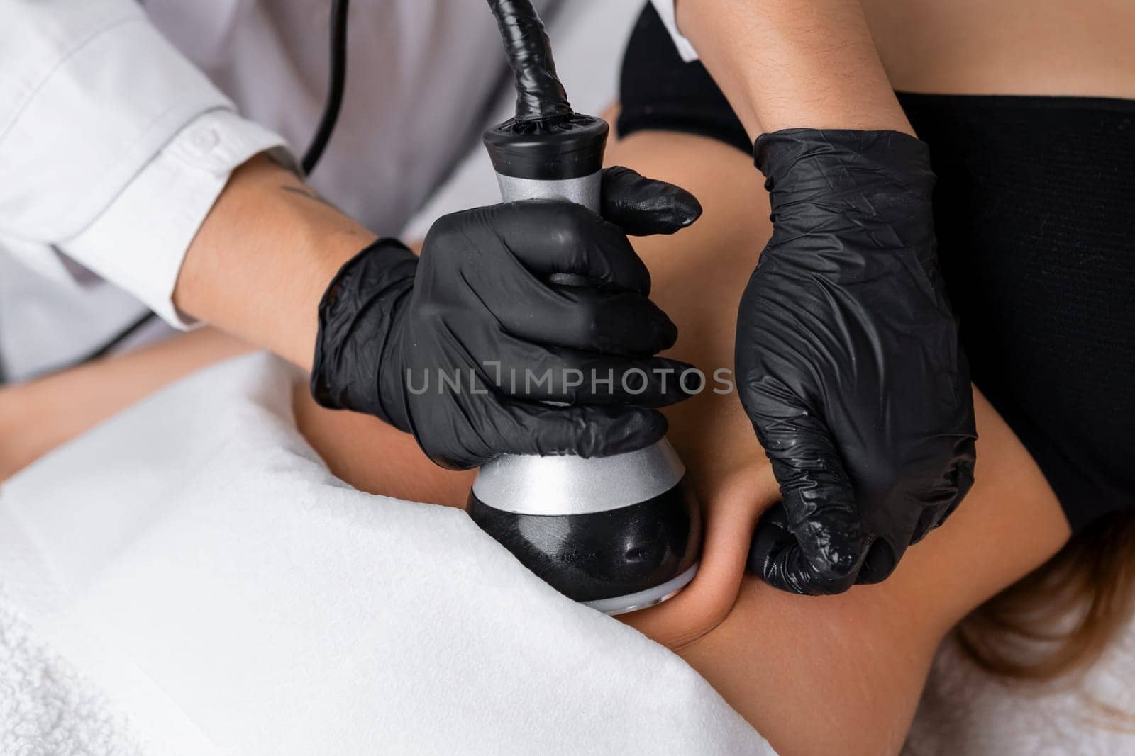 A young woman receiving ultrasound cavitation treatment for body contouring and anti-cellulite therapy of belly, utilizing hardware-based cosmetology methods