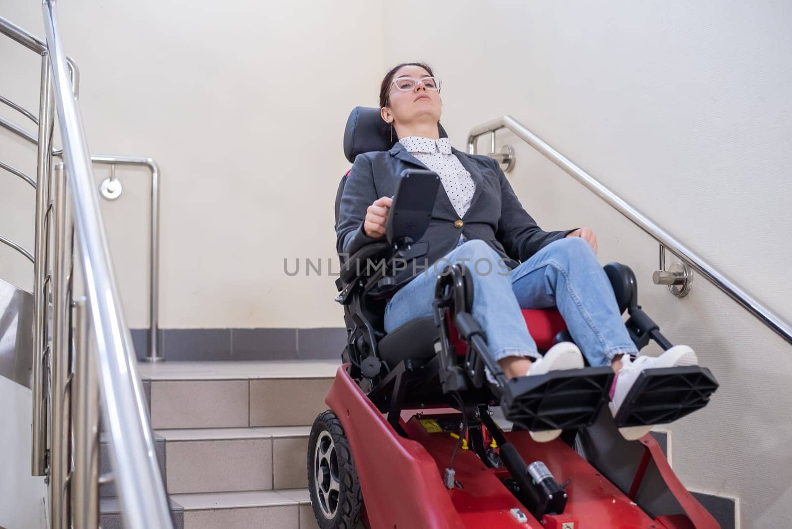 Caucasian woman in electric caterpillar wheelchair climbs up stairs. by mrwed54