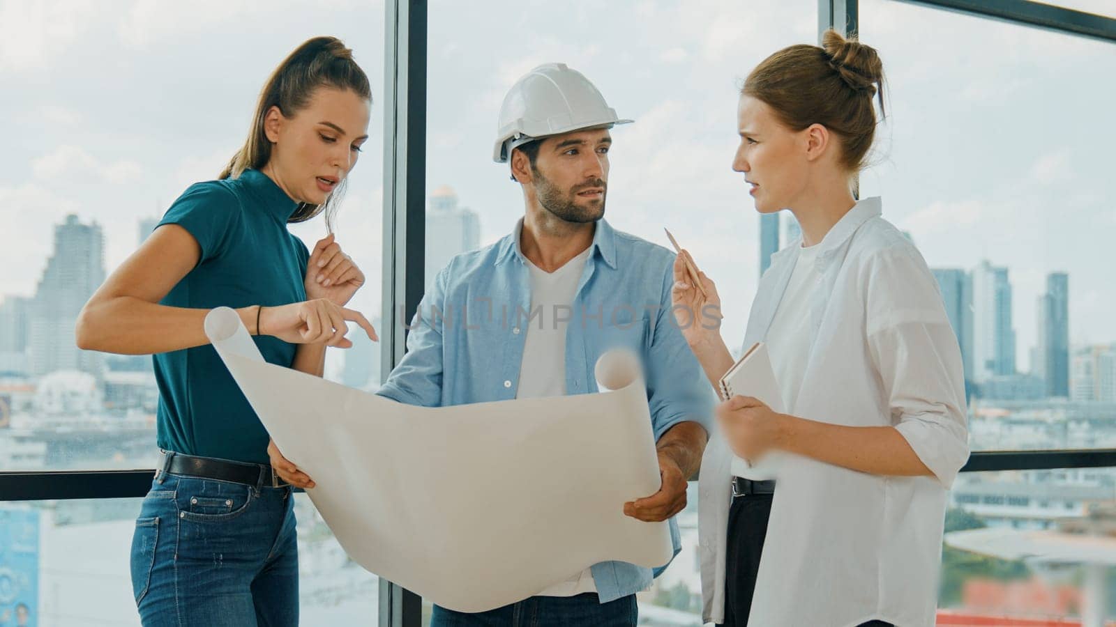 Professional architect engineer team talking, sharing, brainstorming about design while manager hold at project plan. Young architect holding plan while manager listen and point at plan. Tracery