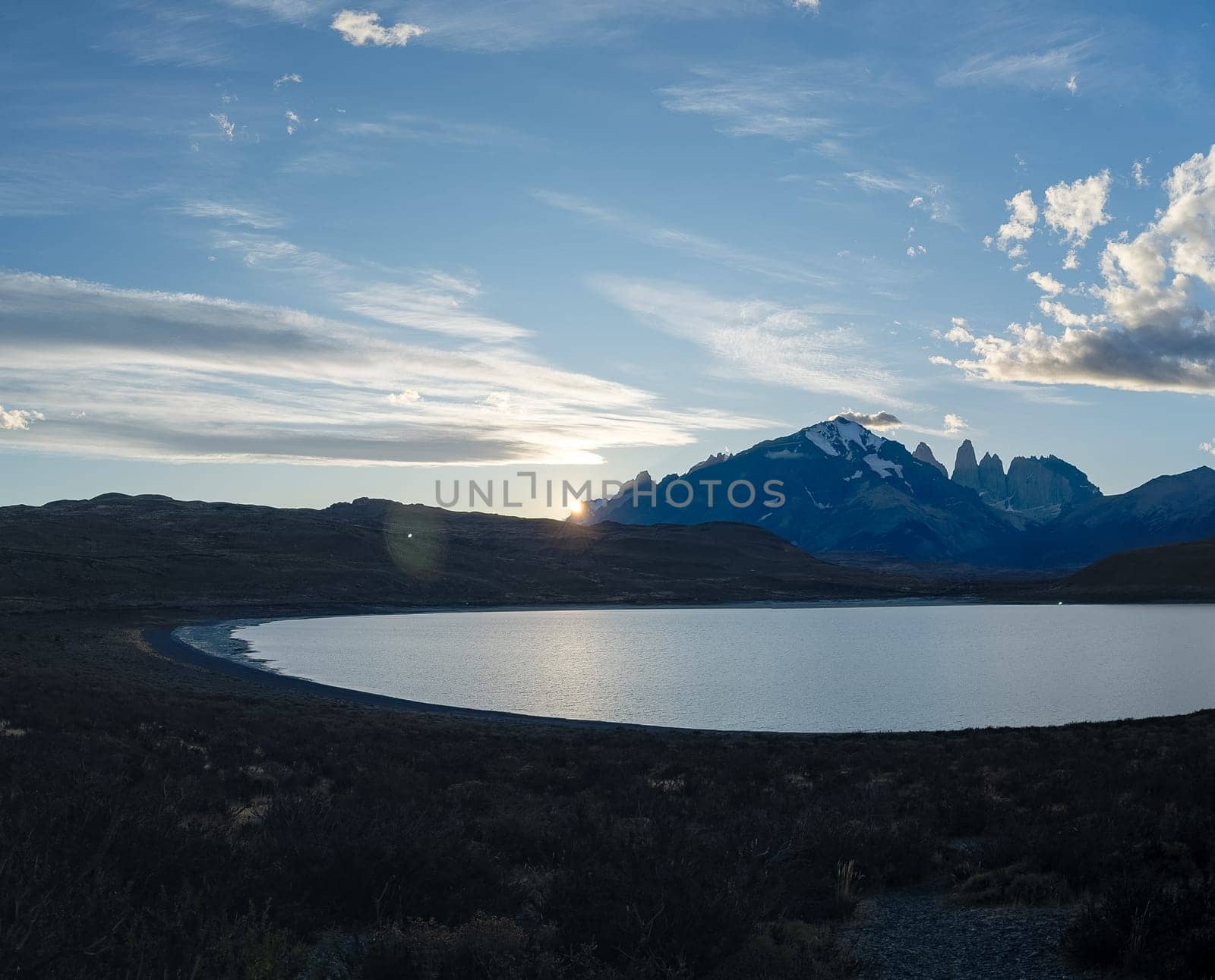 Peaceful dawn lake mirrors rising sun, backed by grand mountains Torres del Paine