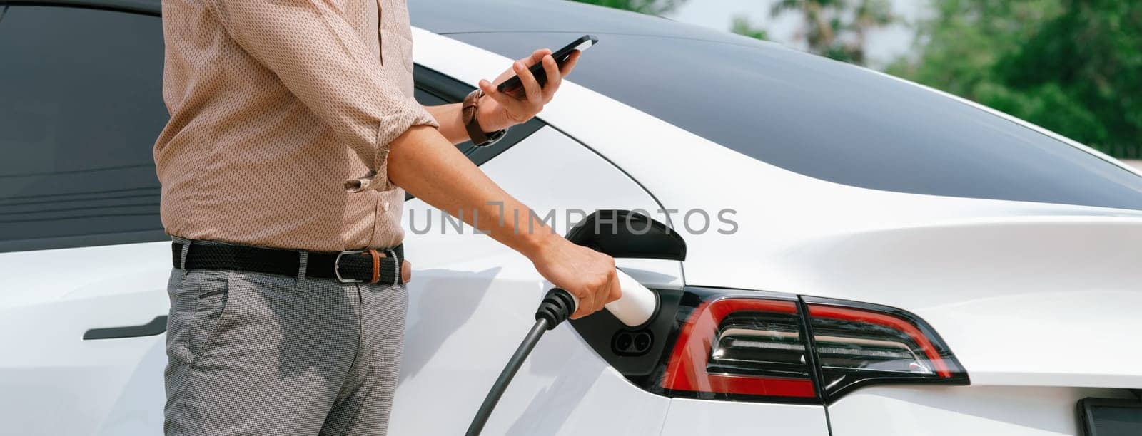 Young man use smartphone to pay for electricity for EV car. Expedient by biancoblue