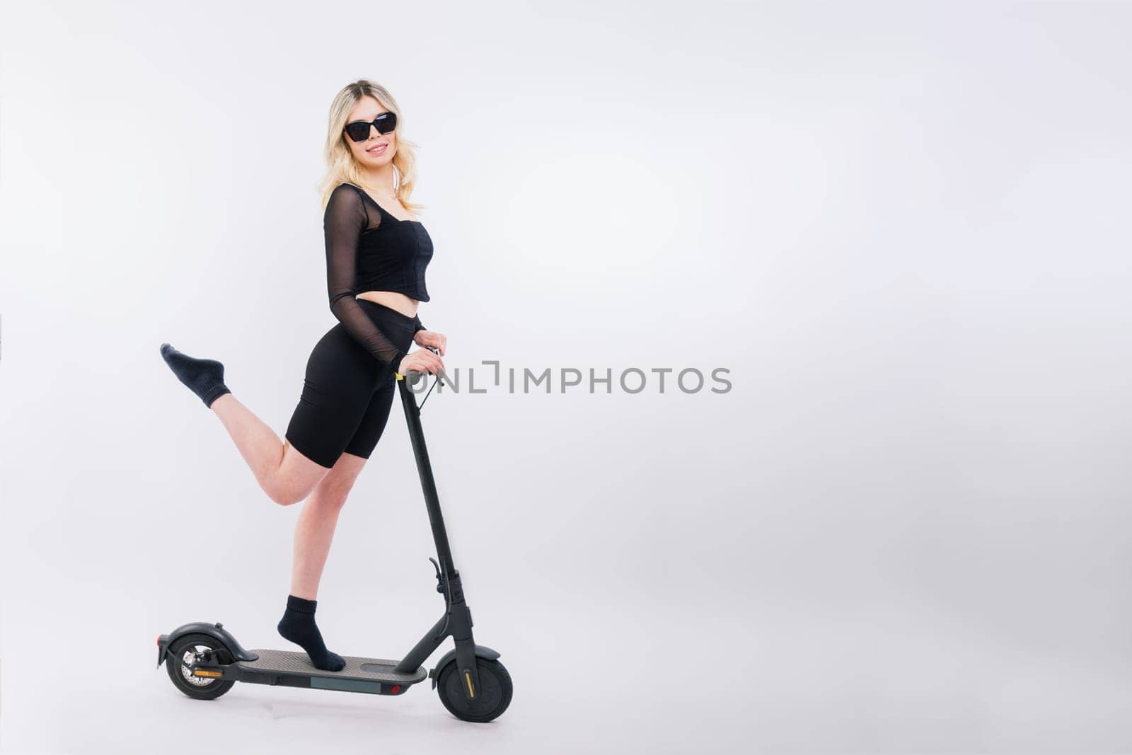 Blonde woman on red white background sitting on electro scooter and resting, copy space by Zelenin