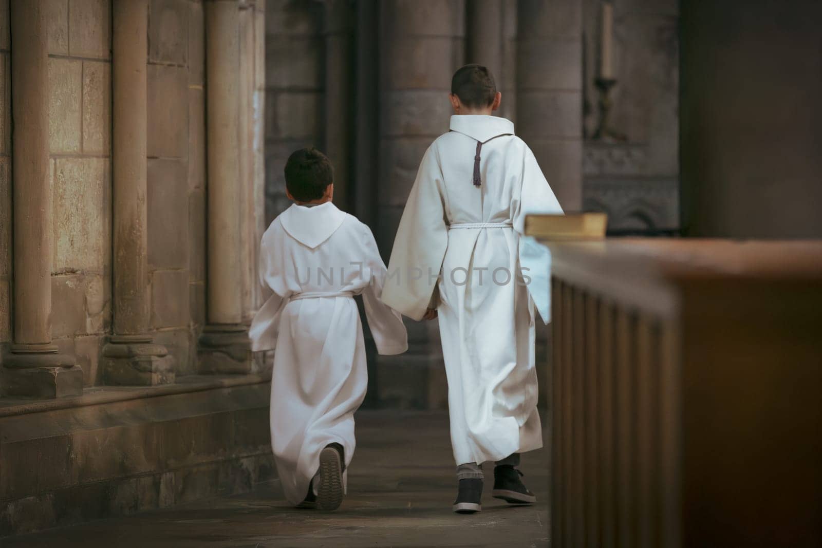 Boys with white tunic dress during communion in the church by Godi