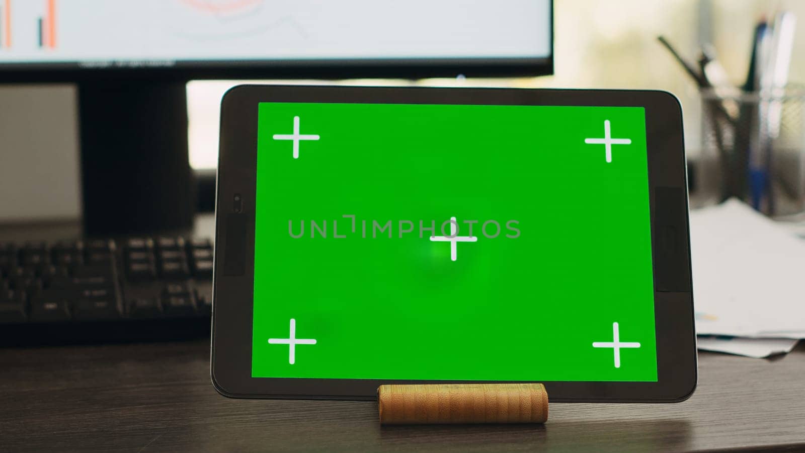 Empty desk with greenscreen on tablet in business coworking space, isolated copyspace layout on modern gadget display. Workstation with device showing chromakey mockup screen.