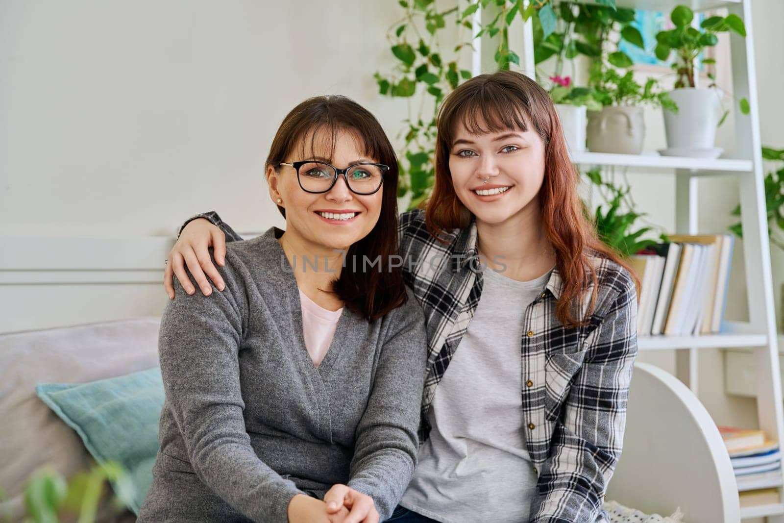Portrait of happy hugging mother and teenage daughter sitting together on couch by VH-studio