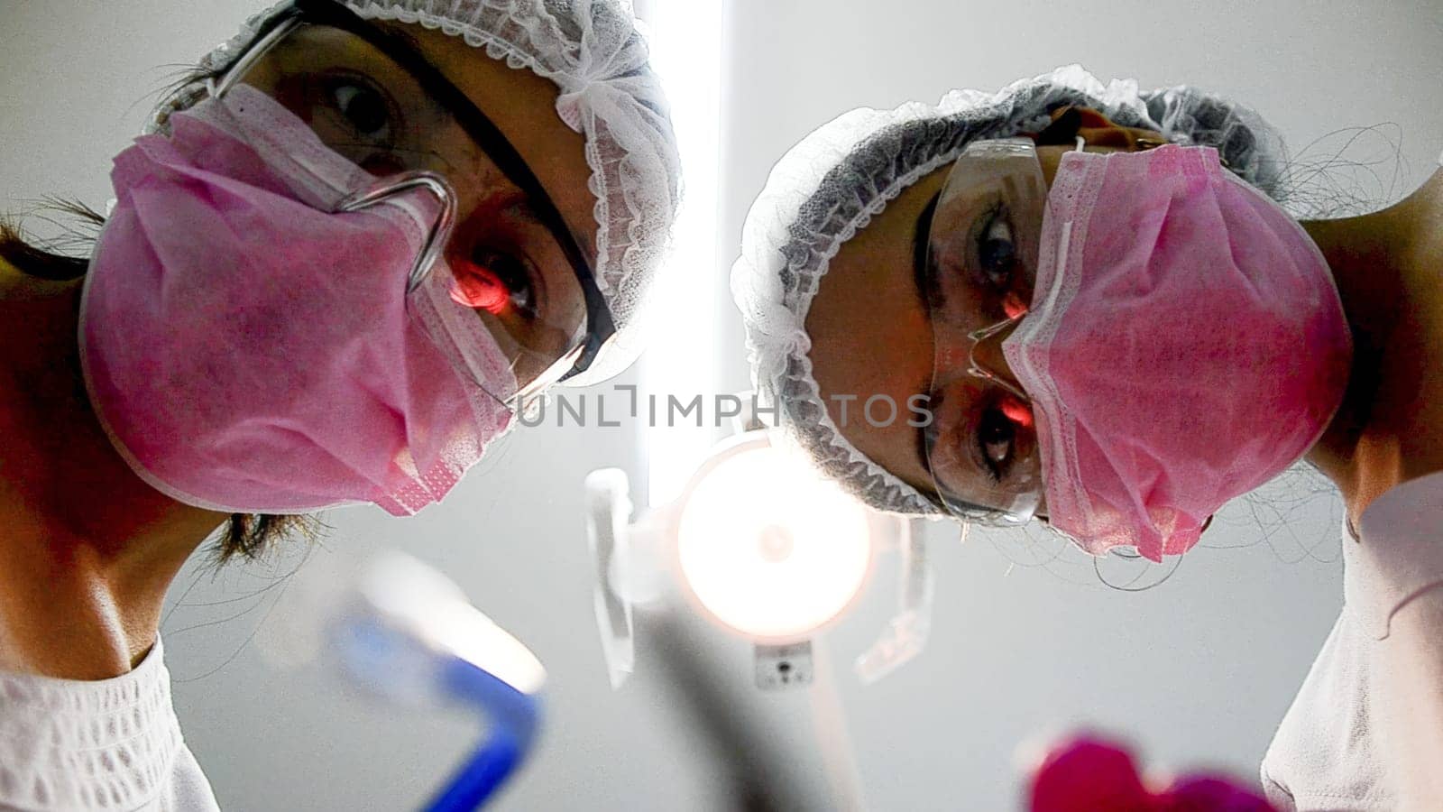 Low angle view of two healthcare professionals wearing surgical masks, seen from a patient's perspective