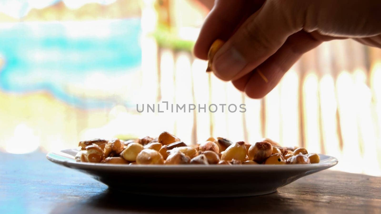 Close-up shot of a hand selecting hazelnuts from a white plate, with a warm, blurry backdrop