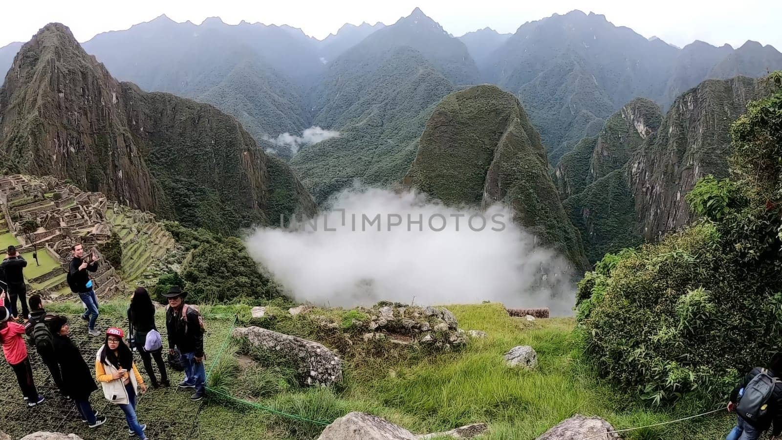 Cusco, Peru - February 12th 2019 : Visitors explore the ancient inca ruins of machu picchu shrouded in a mystical cloud