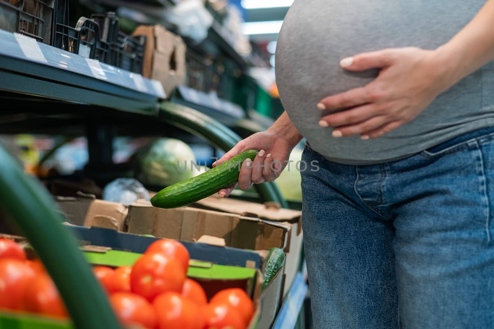 Pregnant woman buys cucumbers in the store. by mrwed54