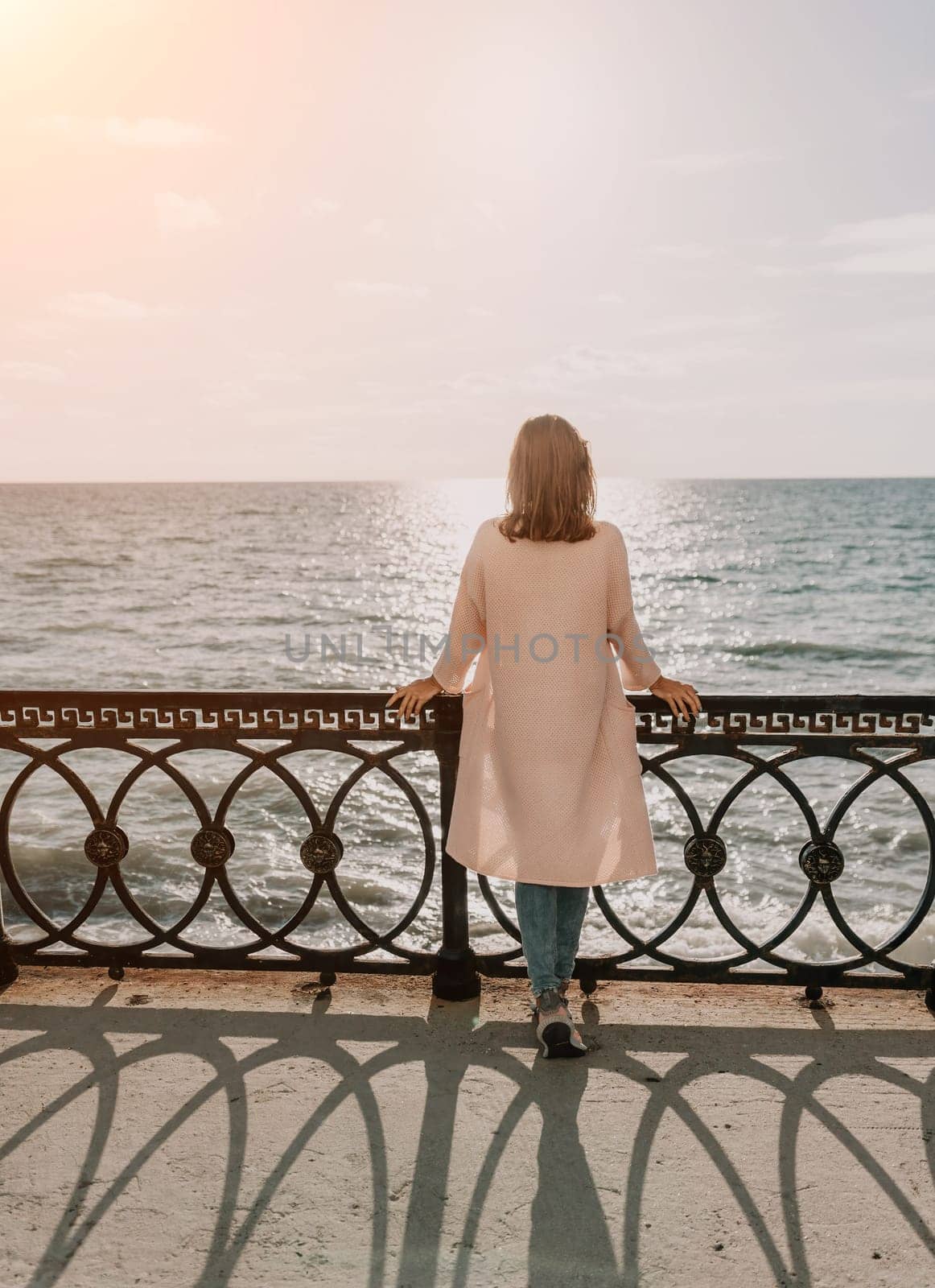 Woman travel sea. Young Happy woman in a long red dress posing on a beach near the sea on background of volcanic rocks, like in Iceland, sharing travel adventure journey