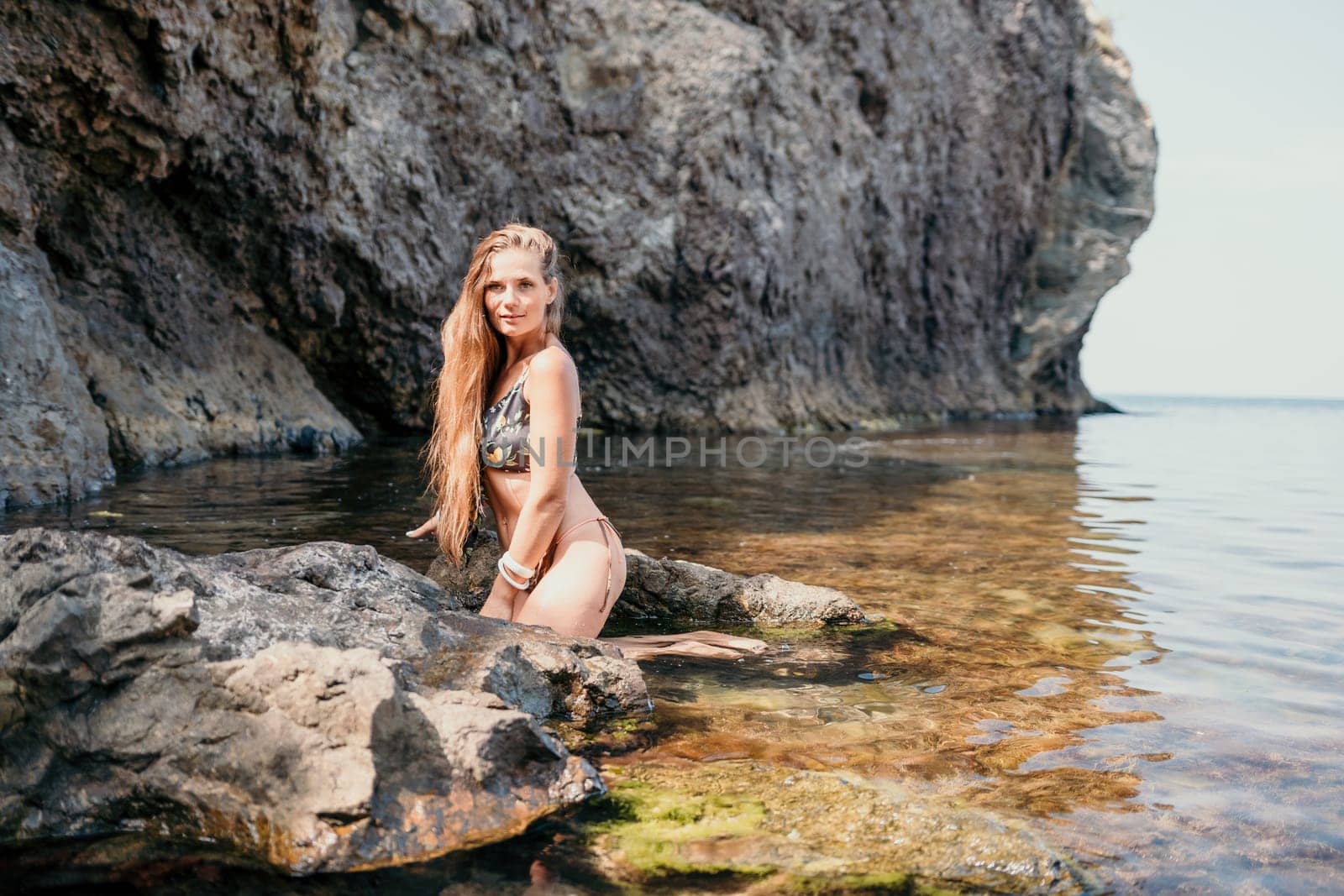 Woman travel sea. Happy tourist taking picture outdoors for memories. Woman traveler looks at the edge of the cliff on the sea bay of mountains, sharing travel adventure journey.