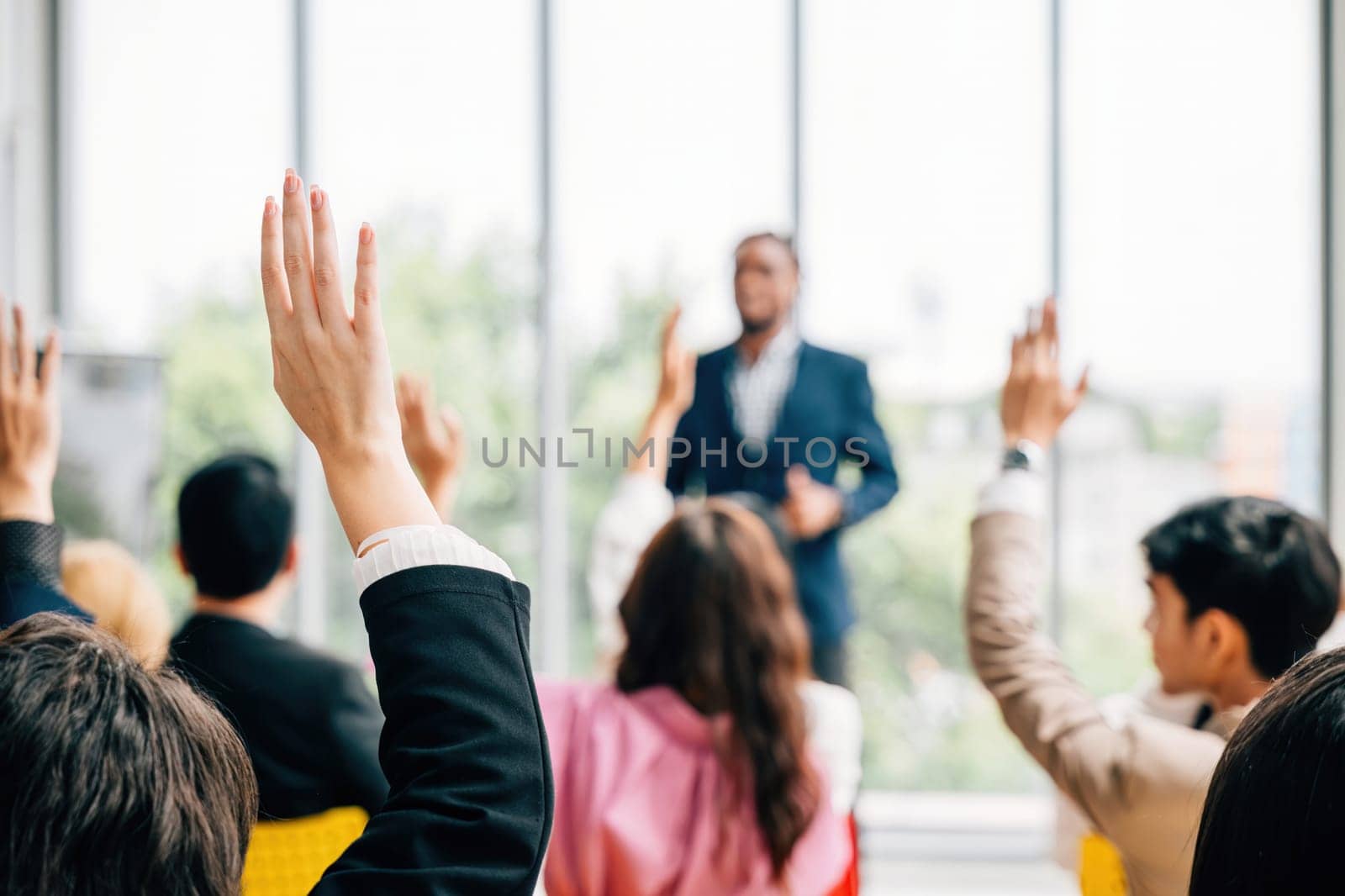 At a corporate event business professionals participate in a conference and convention. Raised hands showcase active involvement in a meeting training seminar and discussions. by Sorapop
