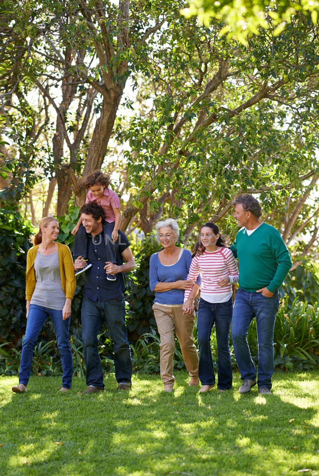 Happy family, conversation and together in outdoor nature, love and bonding or relax in backyard. Generations, smile and peace or communication for support in garden or park, vacation and holiday.