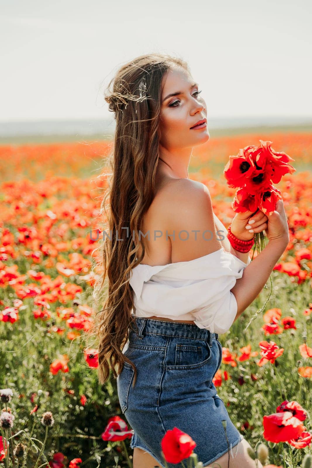 Woman poppies field. Side view of a happy woman with long hair in a poppy field and enjoying the beauty of nature in a warm summer day. by Matiunina