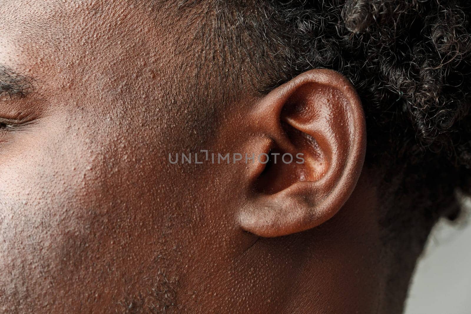 Close-Up View of African Mans Hair and Ear Against a Grey Background studio shot