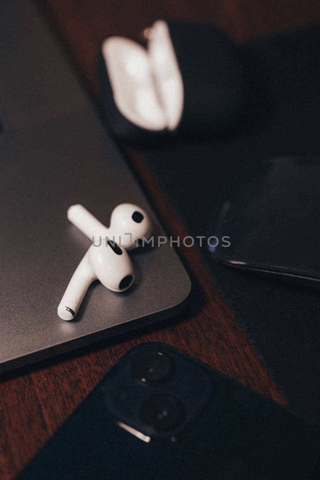 Elegant wireless earphones on top of a laptop. by Pukhovskiy