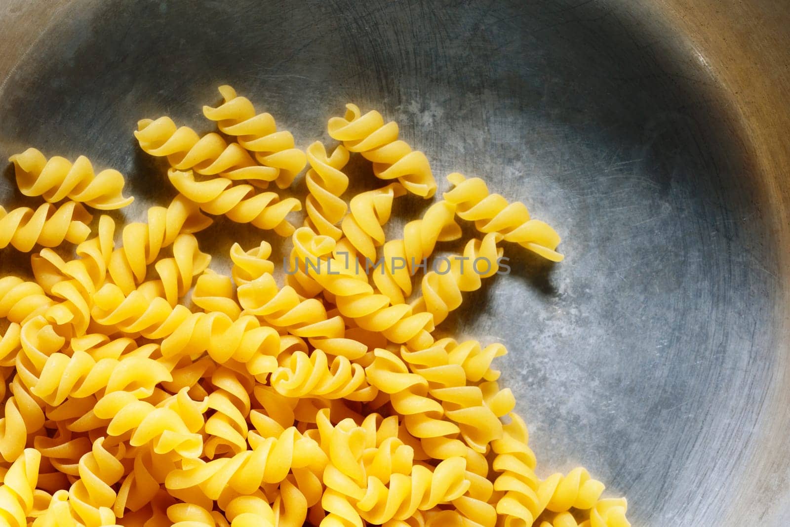  Overhead view of bowl of uncooked fusilli pasta  , helicoidal shape pasta