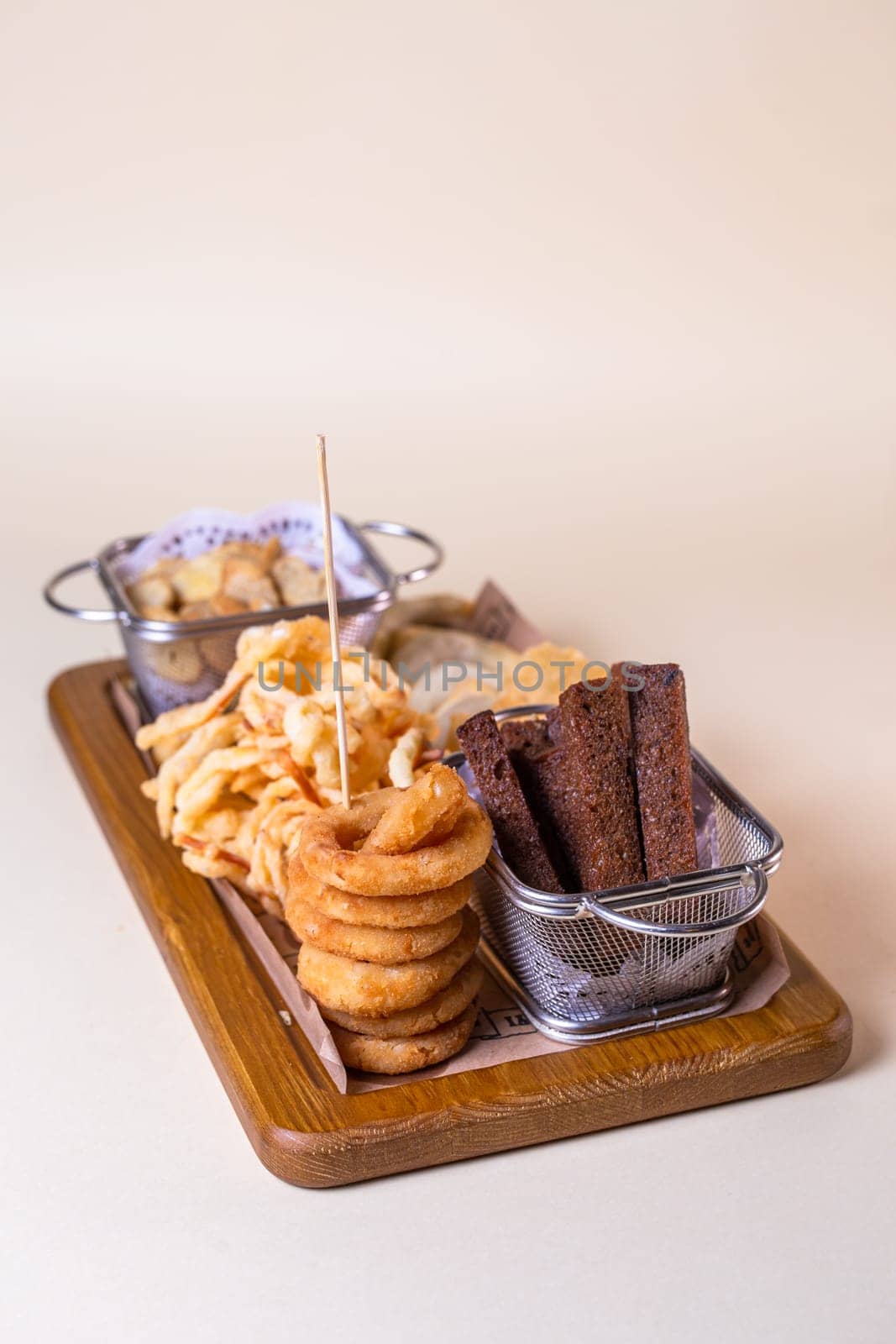 Beer platter with croutons, onion rings, chips on a wooden board by Pukhovskiy