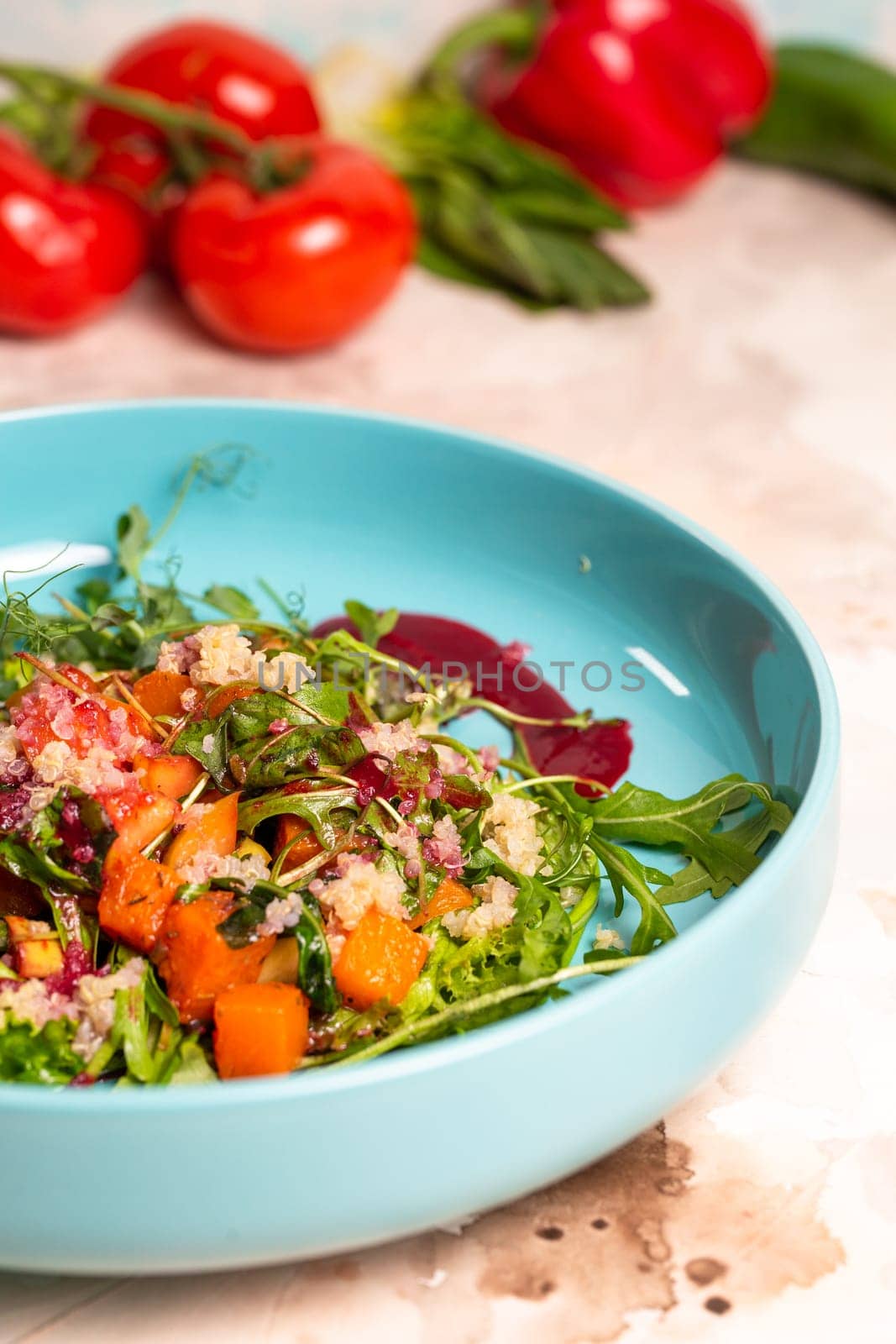 Salad with pumpkin, lettuce, tomatoes, and quinoa. Drizzle with beet sauce and decorate with herbs. Isolated on a white background.