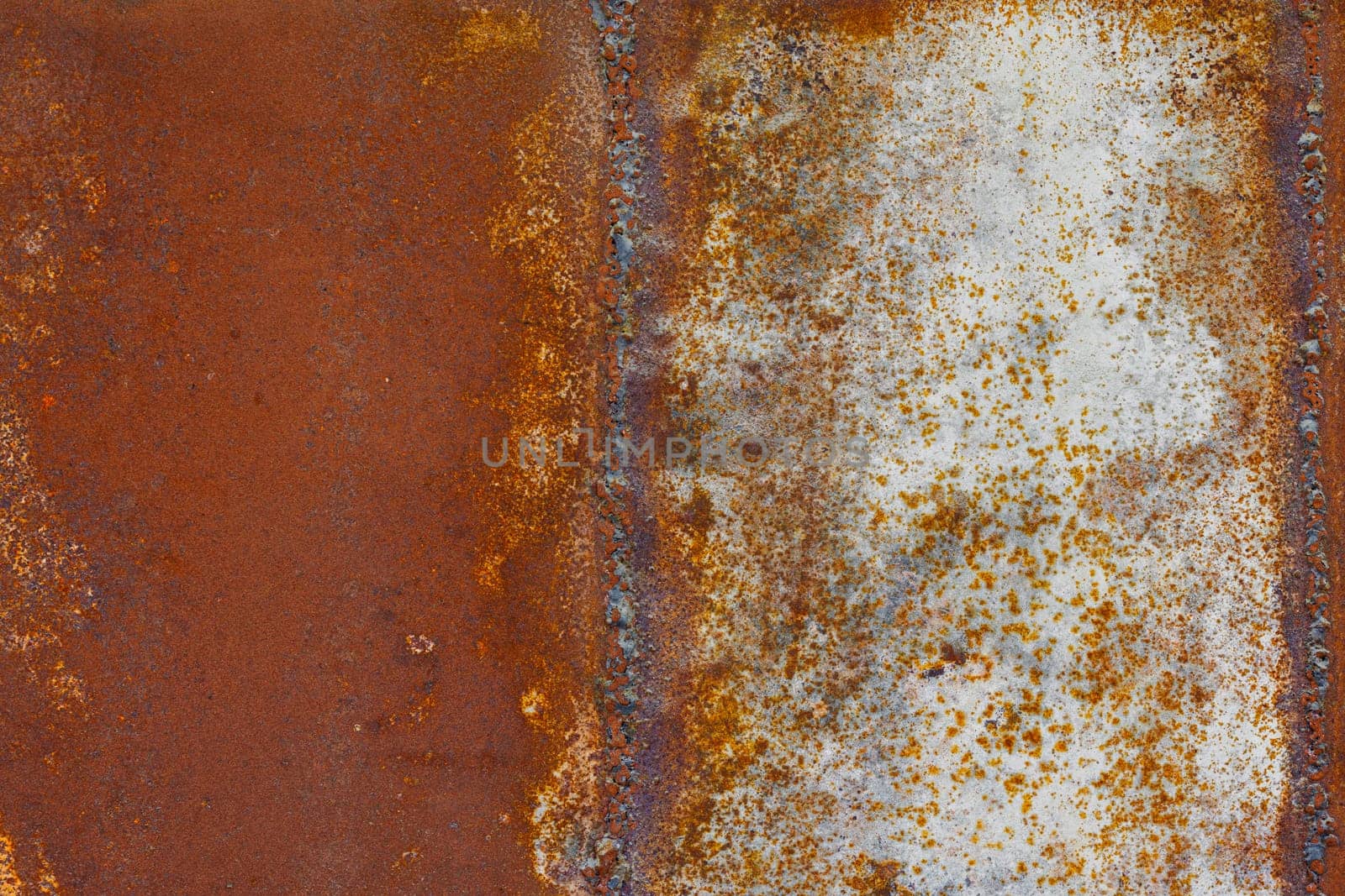 Close up of a brownish rusted welded sheet metal surface with yellowish and orange hue by z1b