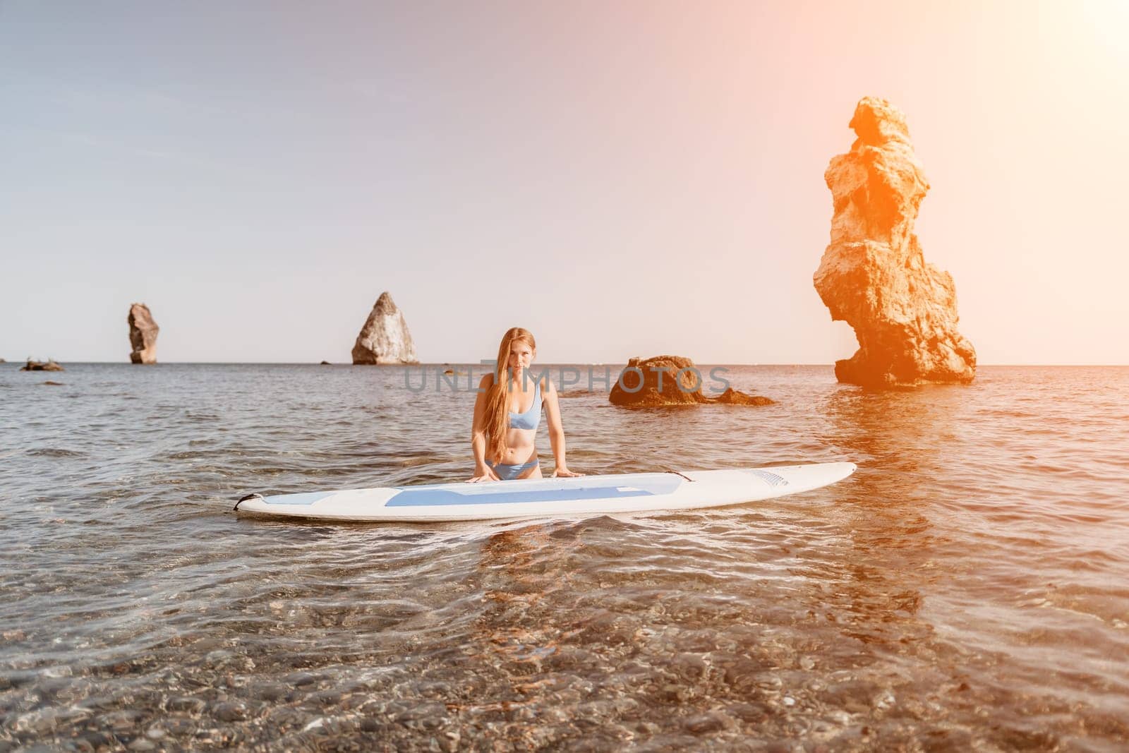 Close up shot of happy young caucasian woman looking at camera and smiling. Cute woman portrait in bikini posing on a volcanic rock high above the sea