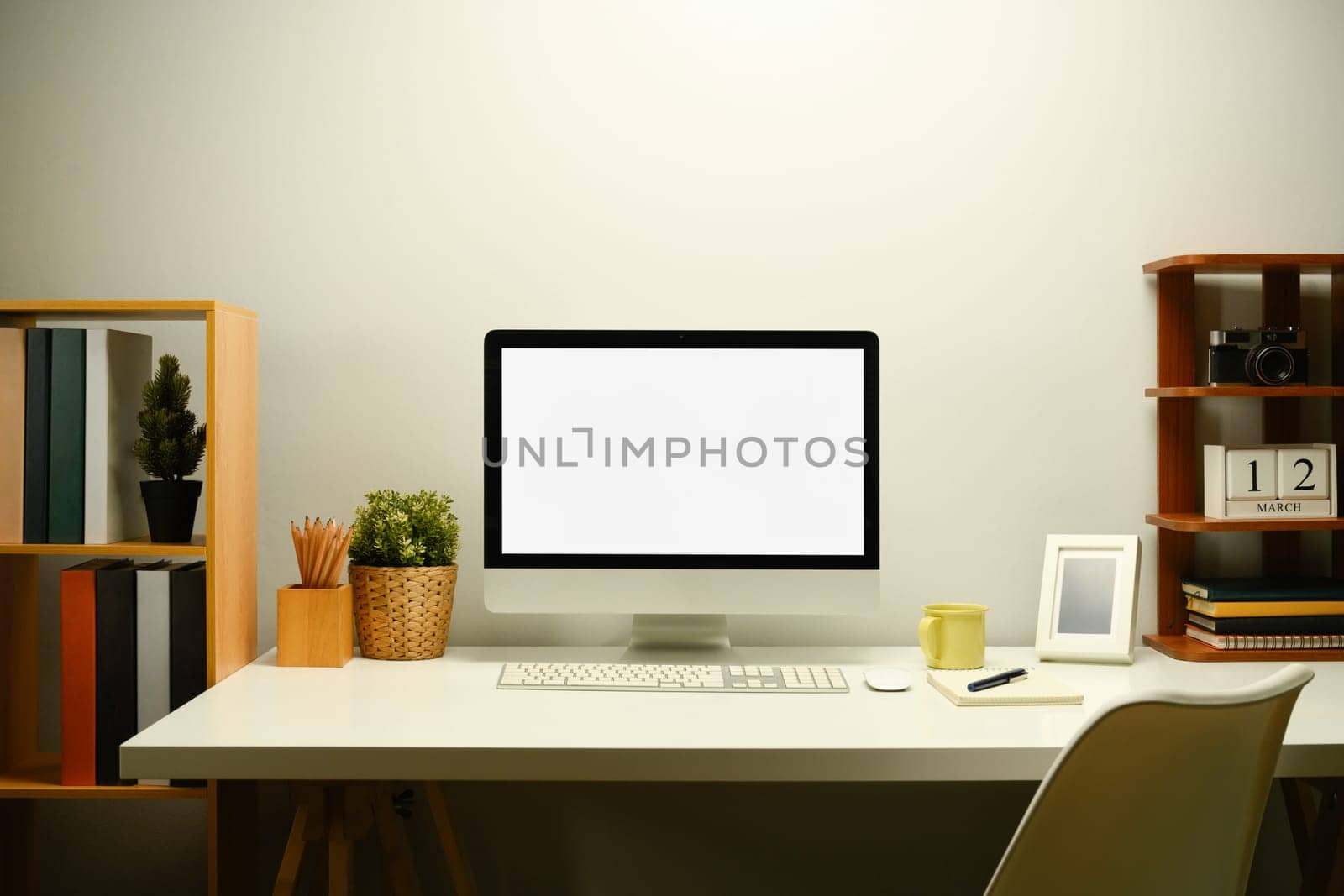 White blank screen computer monitor, houseplant and coffee cup on working table.