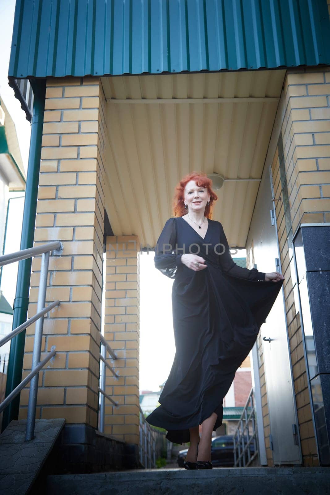 Elegant Woman Twirling in Black Dress on Staircase. Woman in a twirling black dress captured mid-movement on the porch of the house