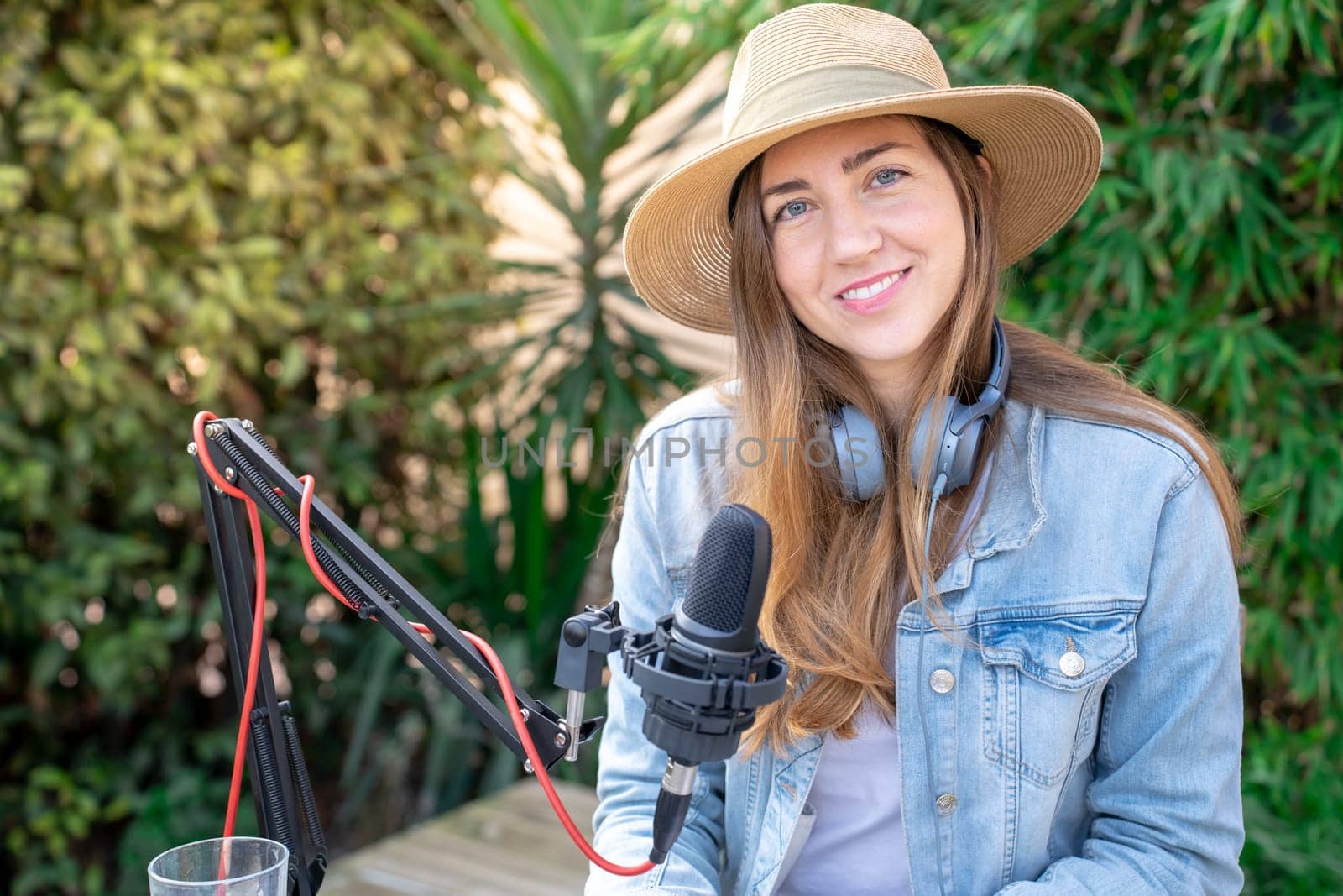 Portrait happy smiling young woman with headphones recording podcast outdoors in spring at sunset. by PaulCarr