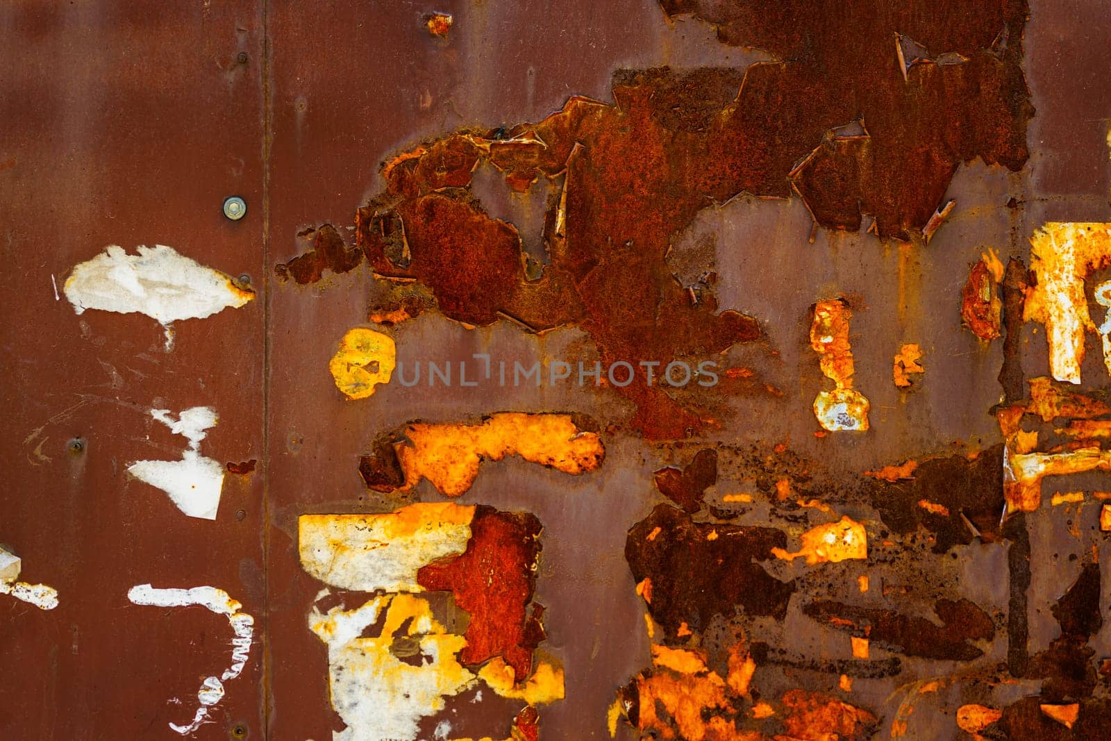 Close up of a brown rusted sheet metal surface with leftovers of peeled off paper advertisements.