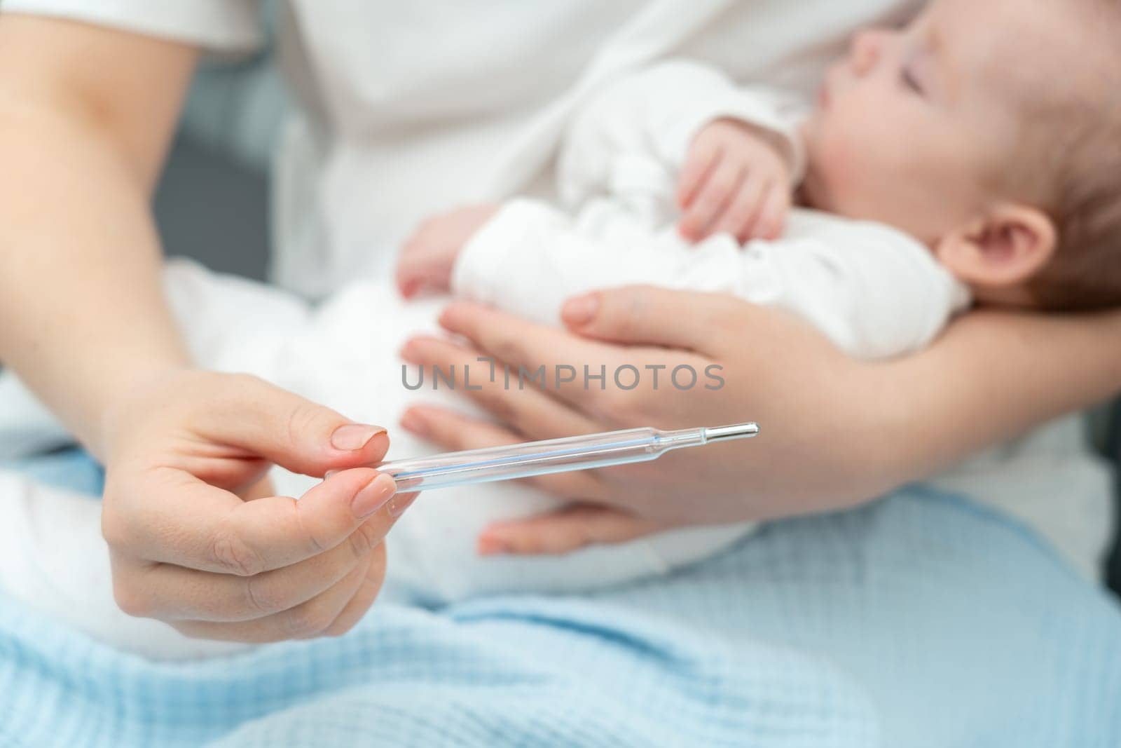 Caring mother precisely measures her newborn's temperature with a mercury thermometer, highlighting