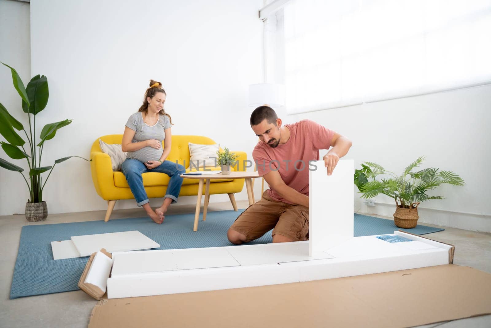 Couple with pregnant woman building new home furniture. High quality FullHD footage