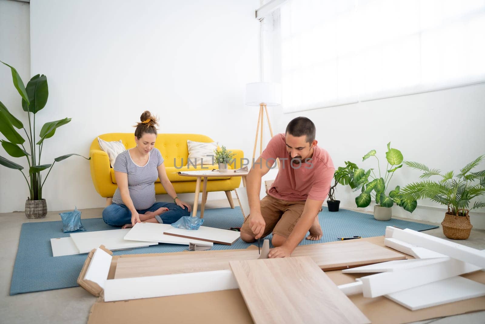 Pregnant couple building furniture in new home. by PaulCarr