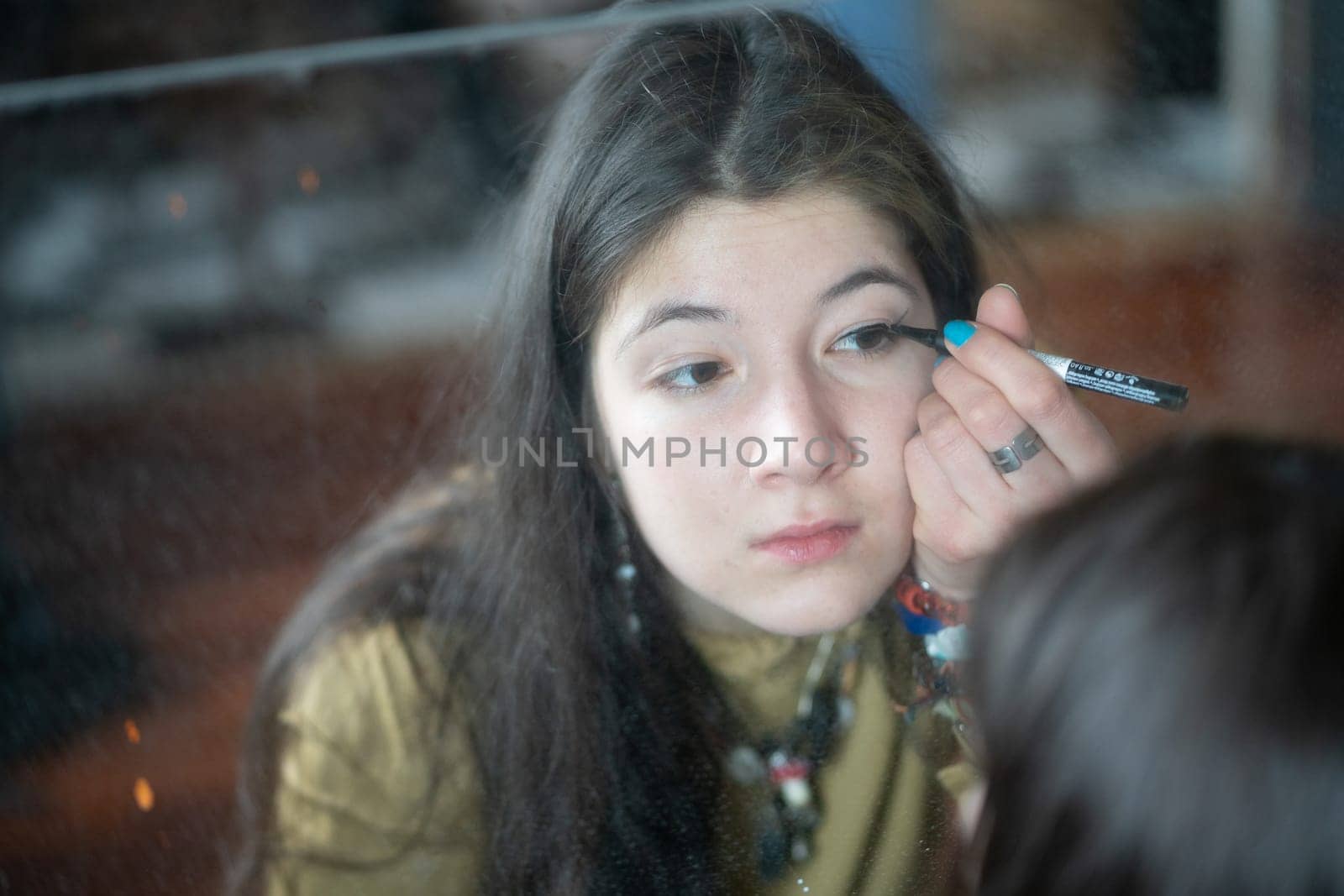 young beautiful woman applying makeup near the mirror