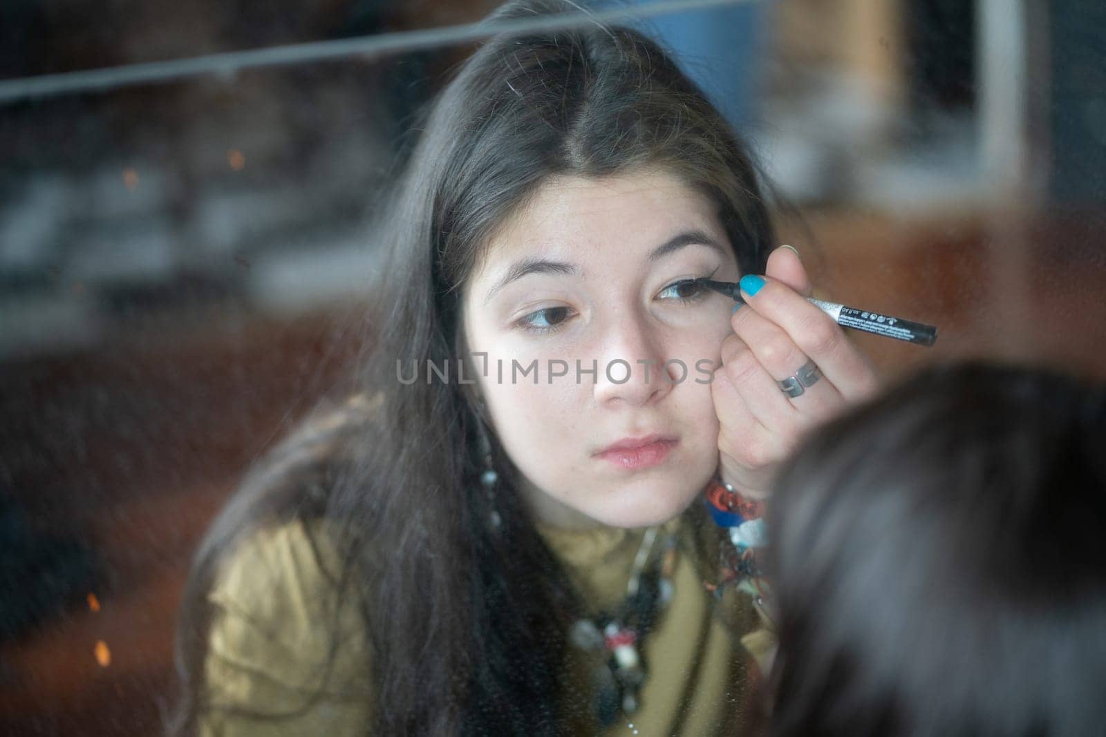 young beautiful woman applying makeup near the mirror