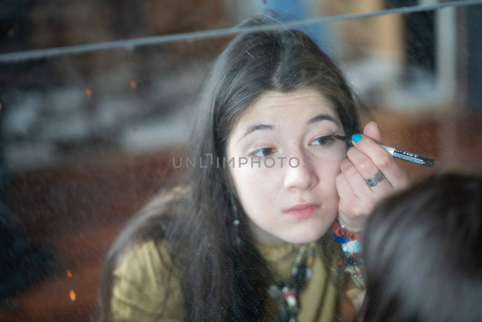 young beautiful woman applying makeup near the mirror